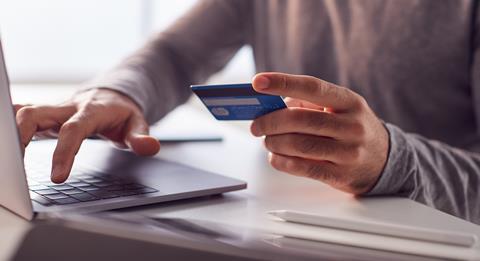 An anonymous man types in his bank card details on a laptop