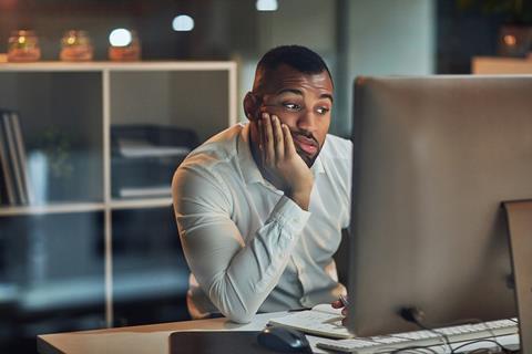 A man sits in front of a computer waiting