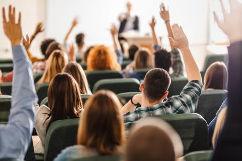 Students raise their hands in a lecture