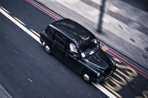 A London cab driving on a road