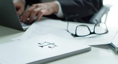 Justice scales on a file next to a laptop