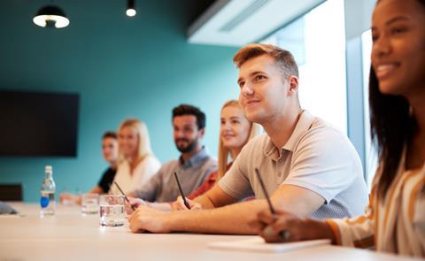 Solicitor apprentices take notes in an office meeting