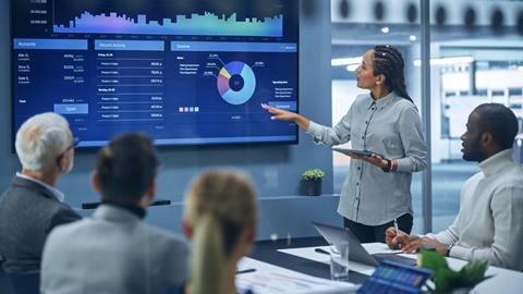 An office worker presents to her colleagues in a meeting