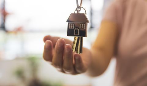 A woman holds out her hand to receive a set of keys to a new house