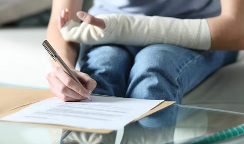 A person fills out a claim form while wearing an arm cast