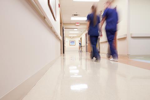 Blurred image of medical staff walking down hospital corridor