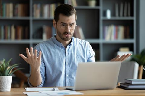 A man looks perplexed as he works on his laptop