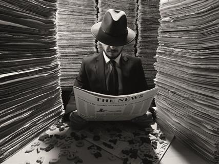 Reporter reading a newspaper surrounded by piles of news