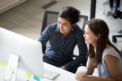 Two female colleagues work together at a computer