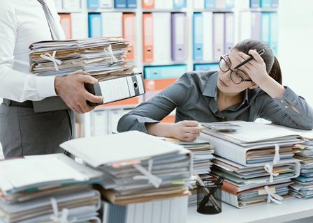 Office worker looks through piles of files