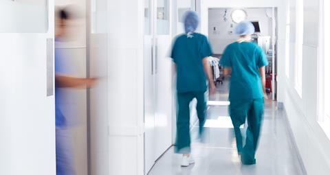 Surgeons wearing scrubs walk to theatre in hospital