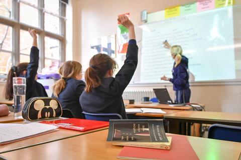 School pupils raise their hands in a lesson