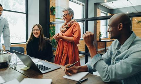 Colleagues laugh together in the office