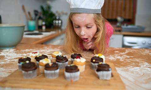 A young girl admires freshly baked cupcakes