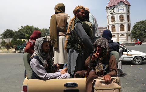 Taliban fighters are seen on a military vehicle in Kabul