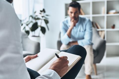 A counsellor takes notes with a client