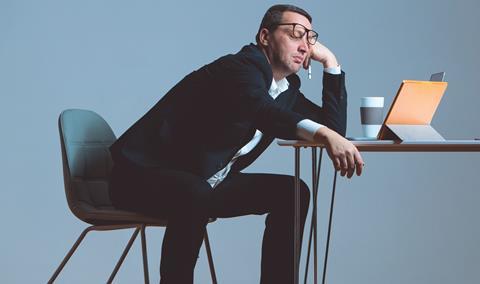 A male office worker falls asleep in front of his laptop