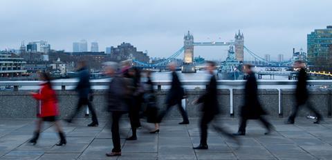 Commuters walk across London Bridge