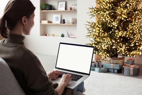 A woman works on her laptop in front of a christmas tree