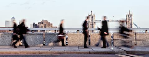 Blurred commuter figures walk with Tower Bridge in the background