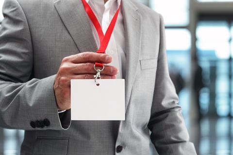Anonymous man wearing a suit holds up his ID card