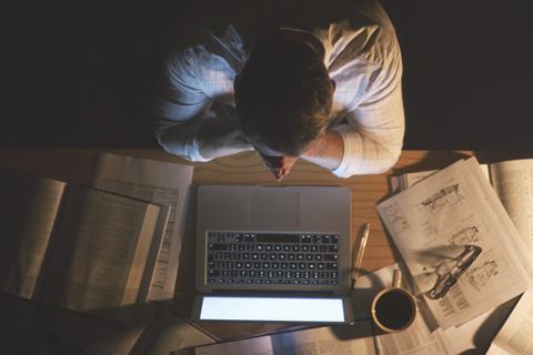 Anonymous man sat at desk works late at night