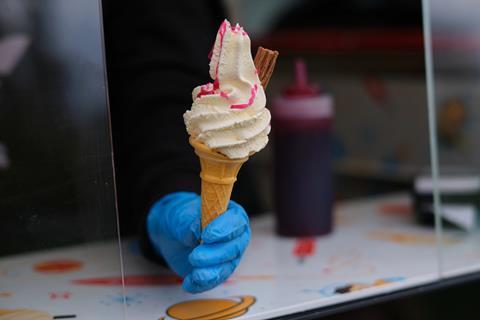 A ice cream van driver hands a 99 cone to a customer