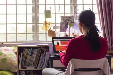 Teenage girl sat at bedroom desk working on laptop