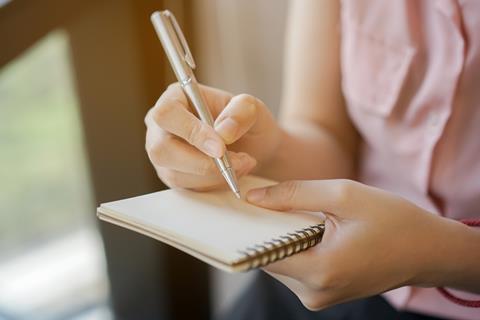 A court reporter writes in a notebook
