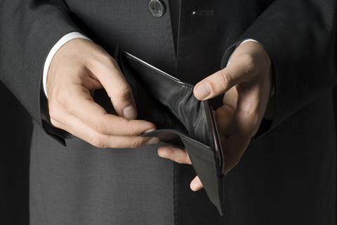 A man wearing a suit opens an empty wallet
