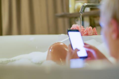 A woman on her phone in the bath