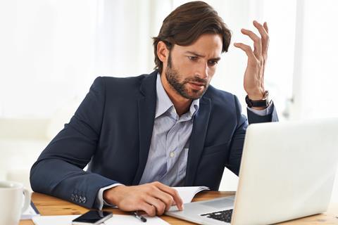 Man looks at laptop in confusion