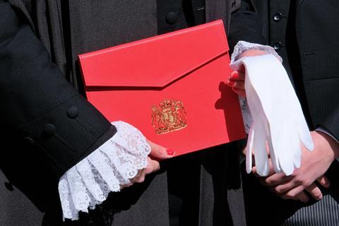 Newly appointed legal member of the King's Counsel (KC) poses with letters of patent and white gloves on 'Silks Day'