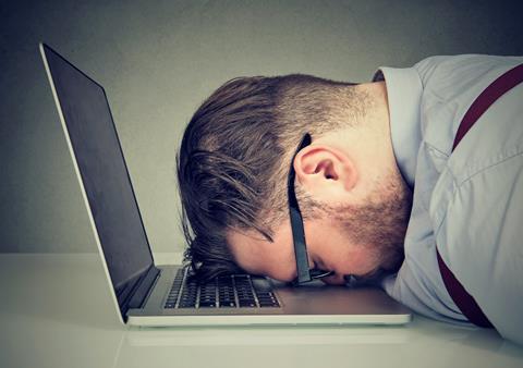A man places his head on his laptop keyboard in despair