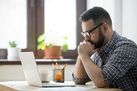 Young man thinking while sat at computer