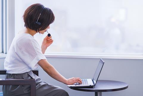 An woman talks into a headset as she takes part in a video call