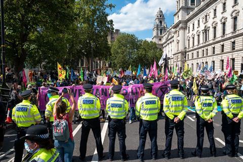 A line of police officers stand in front of a crowd of protesters