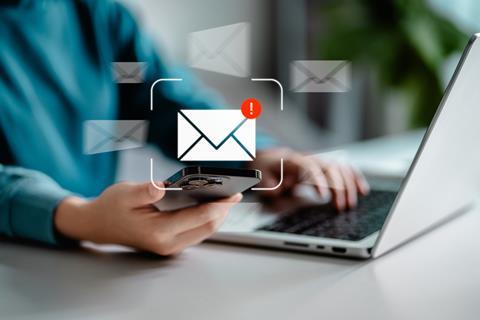Red exclamation mark over an email symbol, with a person working on a laptop in the background